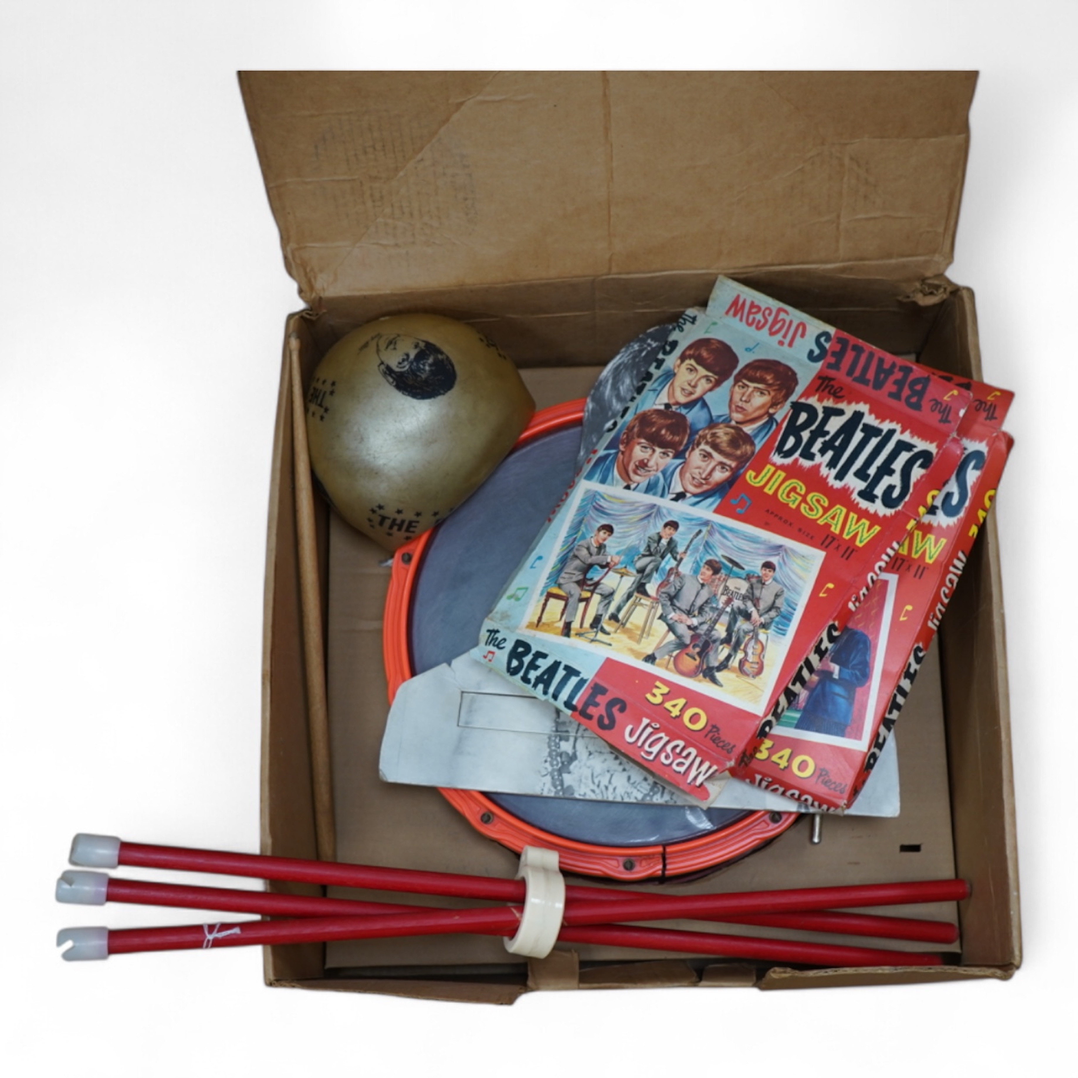 A 1960's Beatles child's plastic drum set in the original card box comprising of a snare drum on a stand, a card cut out bust of Ringo Starr, two 1960s Beatles jigsaws (unchecked) and a Beatles inflatable ball